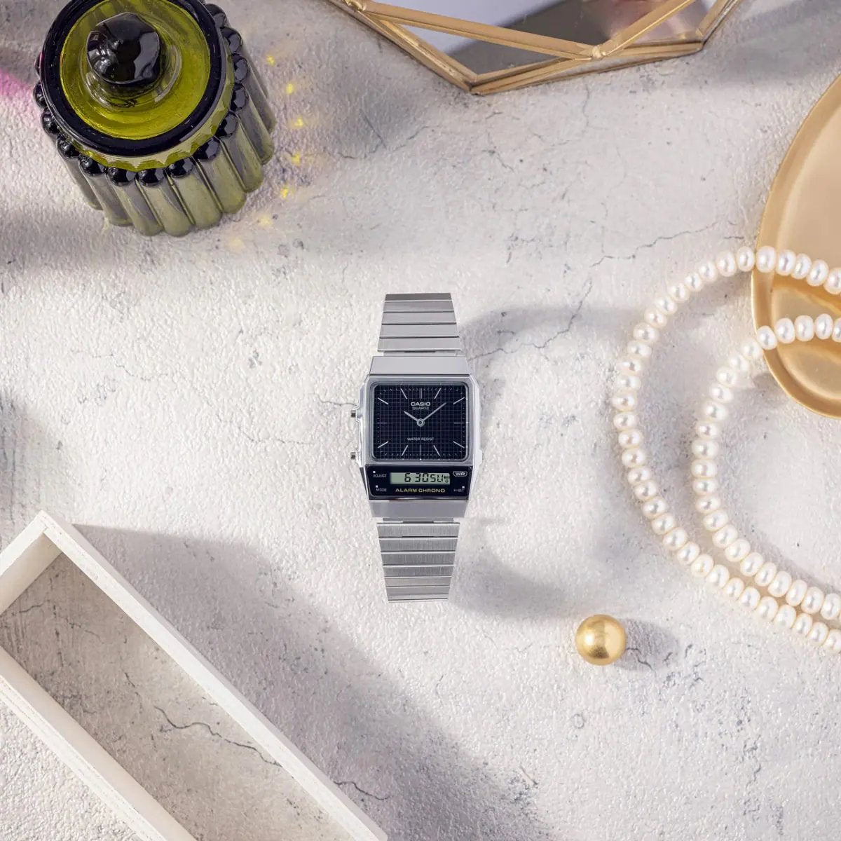 Casio AQ-800E-1A — watch arranged beside jewellery and perfume.