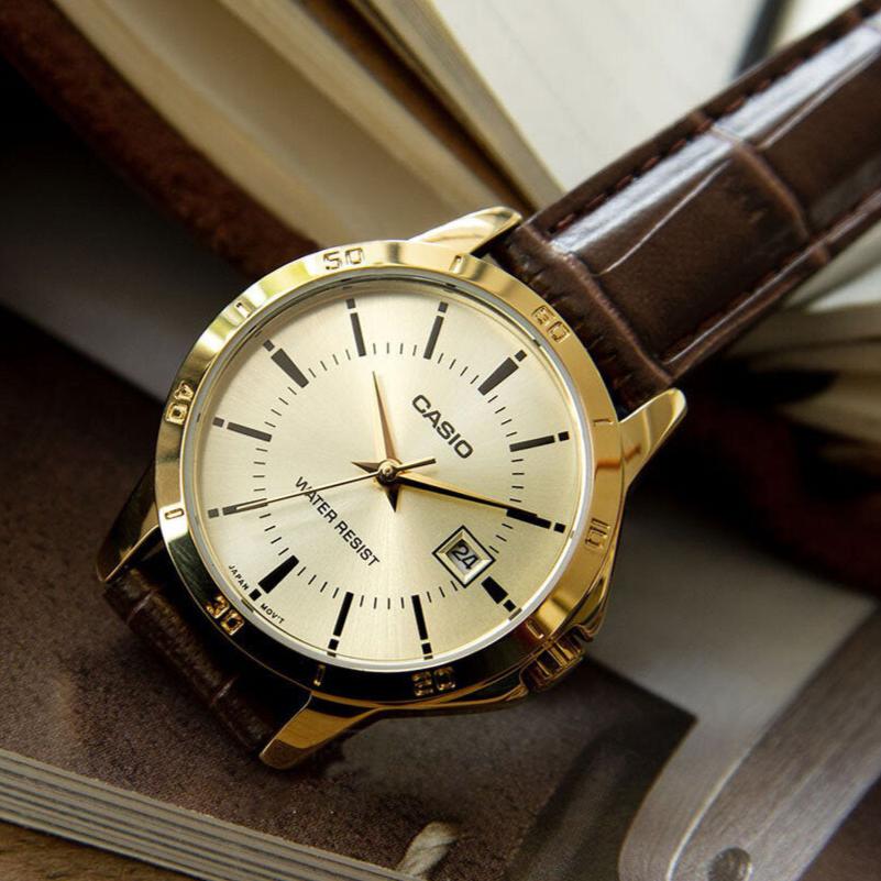 Casio MTP-V004GL-9A — angled watch arranged beside a book.